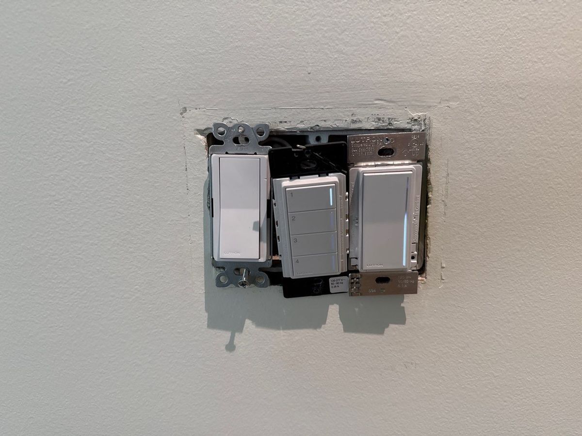 Lutron dimmers and a four-button keypad out of a three-gang wall box during an install