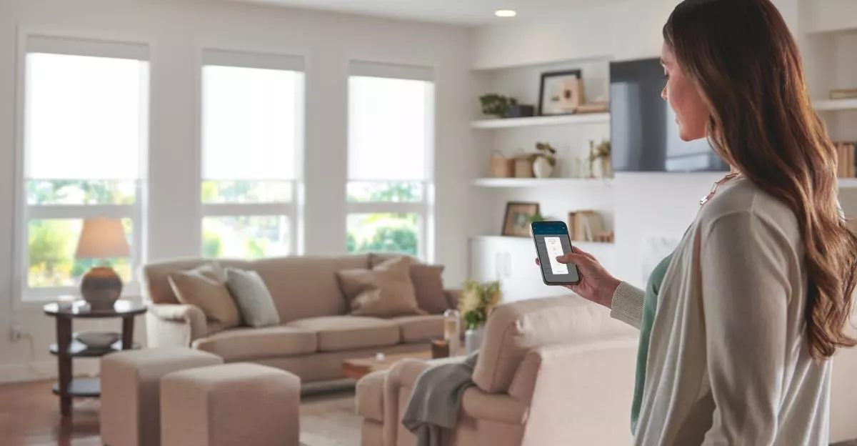 Homeowner adjusting smart shades from her phone in a bright living room